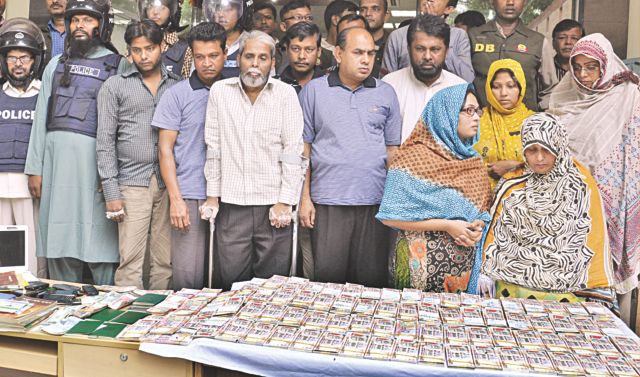Sixteen people, including a former Jamaat leader, an Afghan war veteran and four Pakistani nationals, who were arrested on Friday with bombs and fake currencies, are paraded before the media yesterday. Photo: Banglar Chokh