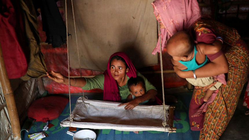 Rohingya refugee women arrange a cradle for child Rohingya refugee women arrange a cradle for child