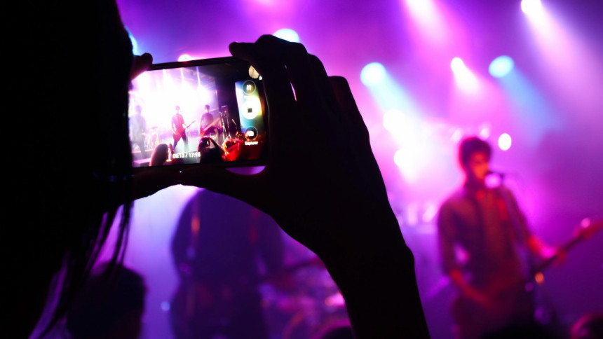 Fan taking photo of performers in a concert