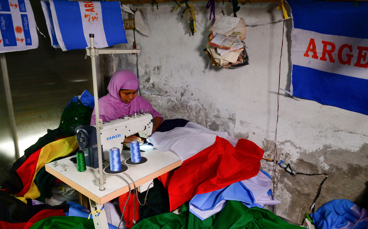 Bangladeshi worker sewing an Egypt flag in Narayanganj, 