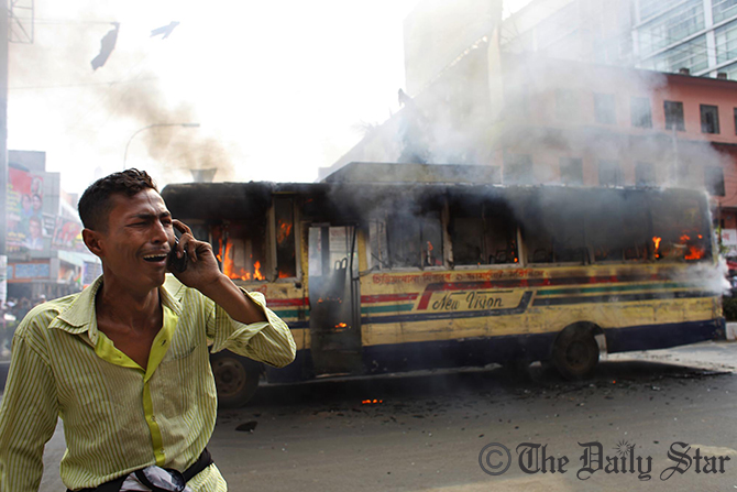 Horrified driver stand in front of his bus as miscreants set fire to it in front of Baitul Mukarram National Mosque on Sunday. Photo: Rashed Sumon