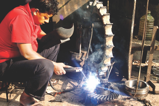 A worker repairing a part of a truck differential that has a broken pinion. Photo: Anisur Rahman