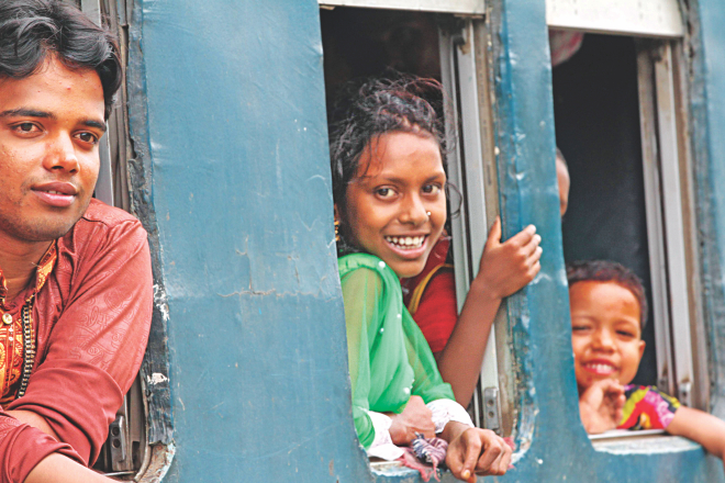 Happy faces at the windows of a train at Airport Railway Station in the capital yesterday. They were the lucky ones who had seats for their travel home on Eid holidays. Many others, not in frame, were standing in the aisle and sitting on the roof of the train. Photo: Sk Enamul Haq