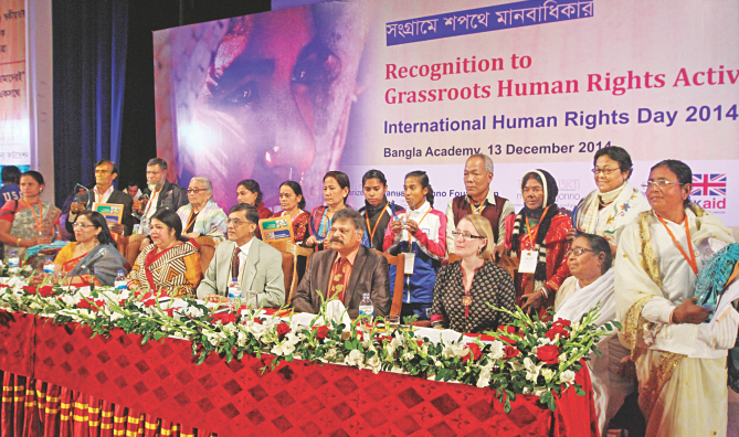 Recipients of the honorary awards given by Manusher Jonno Foundation, standing behind, with the guests sitting in front, in the capital's Bangla Academy yesterday, at the award giving ceremony marking Human Rights Day. Photo: Star