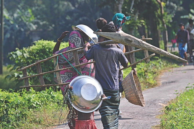 A group of labourers, carrying a handheld plough and a ladder are looking for work in Narsingdi. Photo: Anisur Rahman