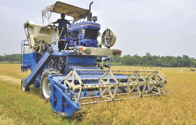 A reaper mounted on a tractor is harvesting rice. File Photo