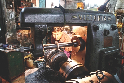 A worker making a gear on a lathe machine. 