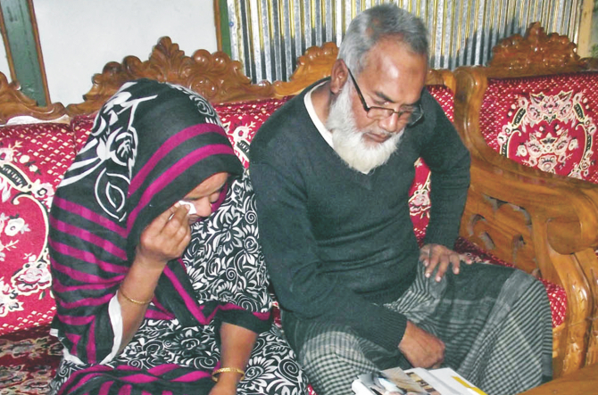 With tears in their eyes, the father and mother of Zubair Ahmed looks at the photos of their son in their home in Kalapara of Patuakhali yesterday after a court in Dhaka sentenced five people to death for the murder of Zubair in 2012. Photo: Banglar Chokha