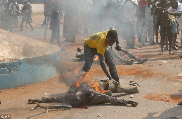 A man who goes by the name of Mad Dog cuts off a portion of a burning body to eat, as the bodies of two lynched Muslim men are burned in a street in Bangui, Central African Republic. Photo: AP