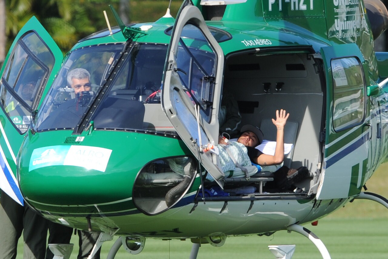 Brazilian striker Neymar waves on July 5, 2014 from inside the helicopter that will transport him from Teresopolis, Rio de Janeiro State, Brazil to his residence in Guaruya. Injured Brazil star Neymar departed his team's training base in Terespolis in a helicopter on Saturday and headed home to Sao Paulo, after his World Cup ended in agony on Friday night. Photo: AFP/ Getty Images