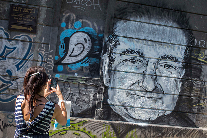 A woman takes a picture of a mural depicting late actor Robin Williams in Belgrade, August 13, 2014. The mural was drawn on a building in downtown Belgrade by an unknown artist on Tuesday. Photo: Reuters